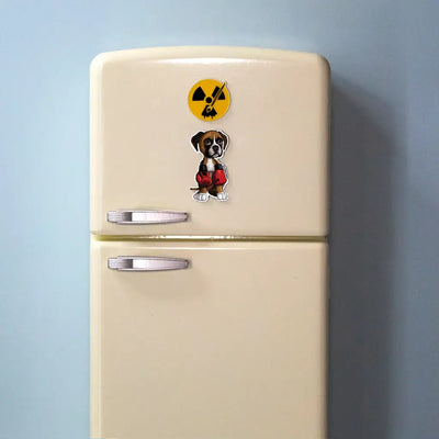 Actual photo of a Boxer puppy magnet on a small cream-colored toy refrigerator. The magnet shows a Fawn Boxer puppy wearing red boxing gloves. Above it is a round yellow Rad Tech Artist logo magnet featuring a radiation symbol with a paintbrush.