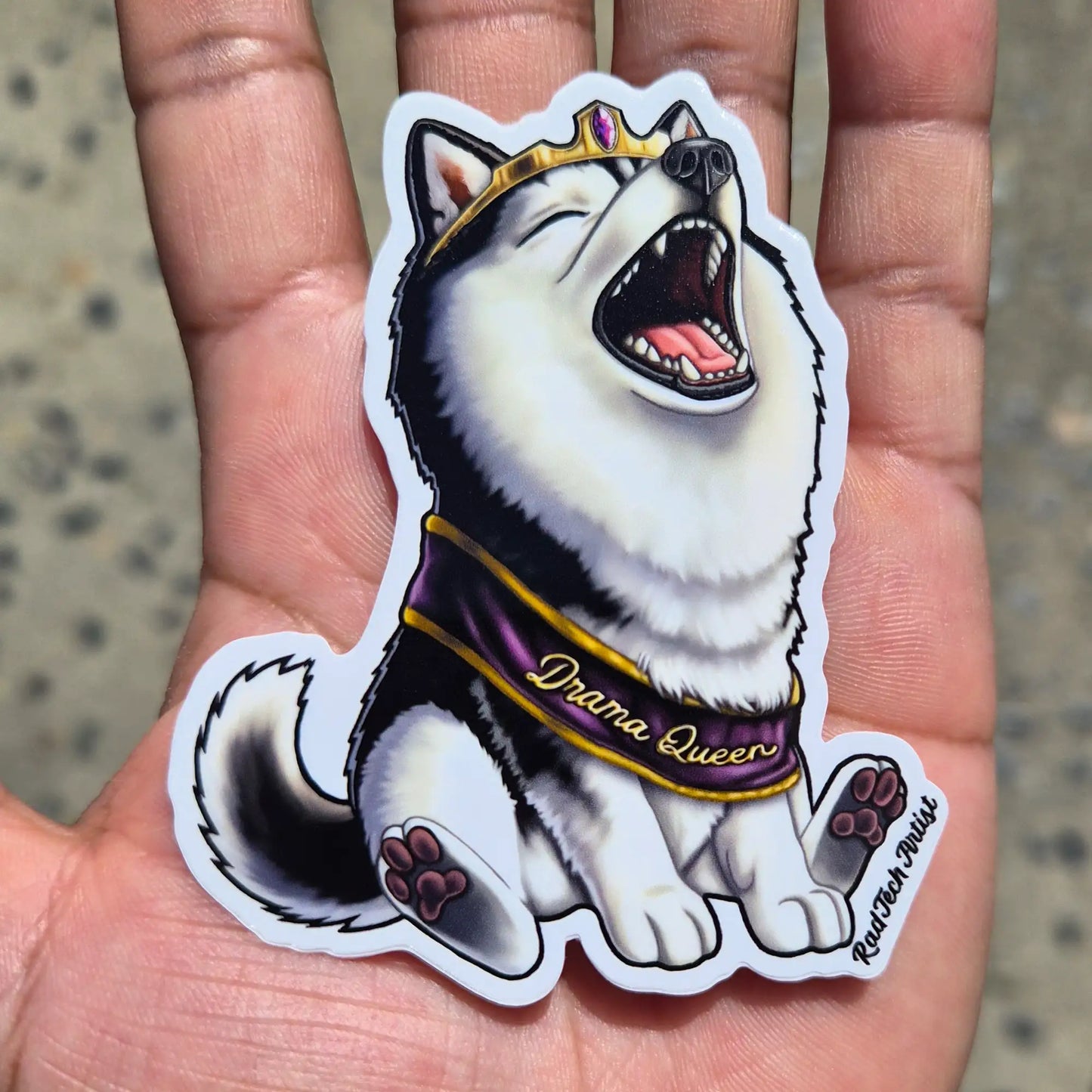 Sticker of a black and white husky dog wearing a tiara and 'Drama Queen' sash on a gray background