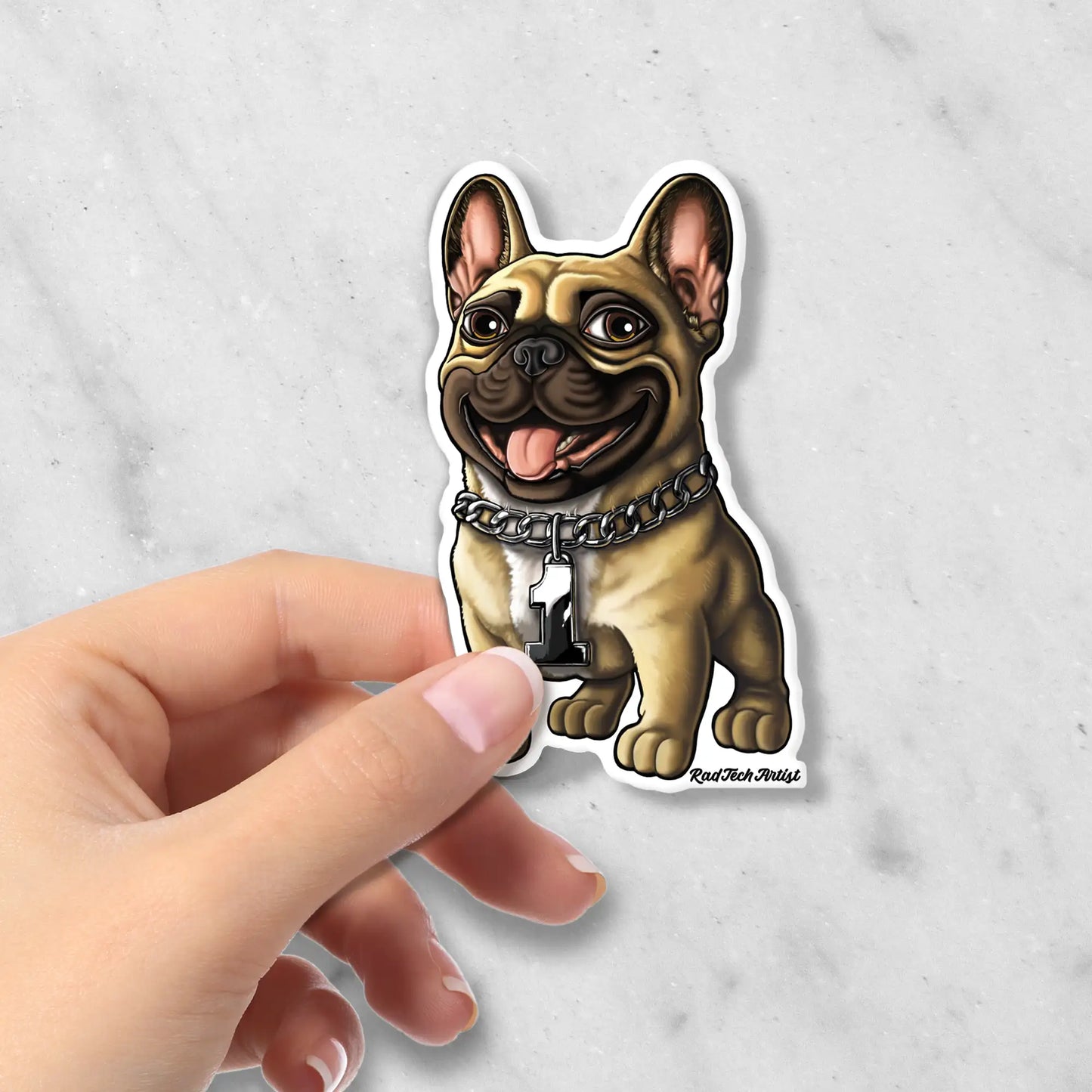 Hand holding a sticker of a fawn French Bulldog with a chain collar on a light gray background