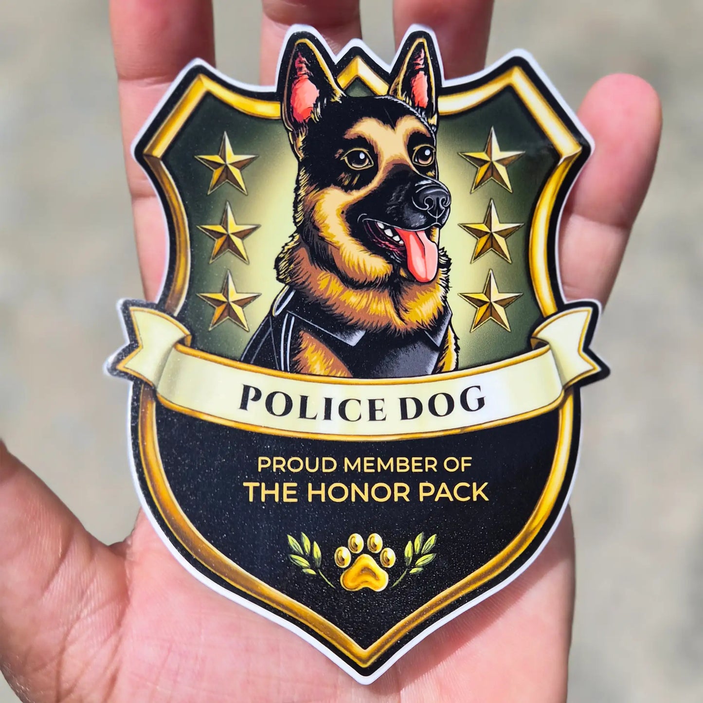 A hand holding a die-cut sticker featuring an illustrated German Shepherd in a police dog badge design with the text 'POLICE DOG' and 'PROUD MEMBER OF THE HONOR PACK'.