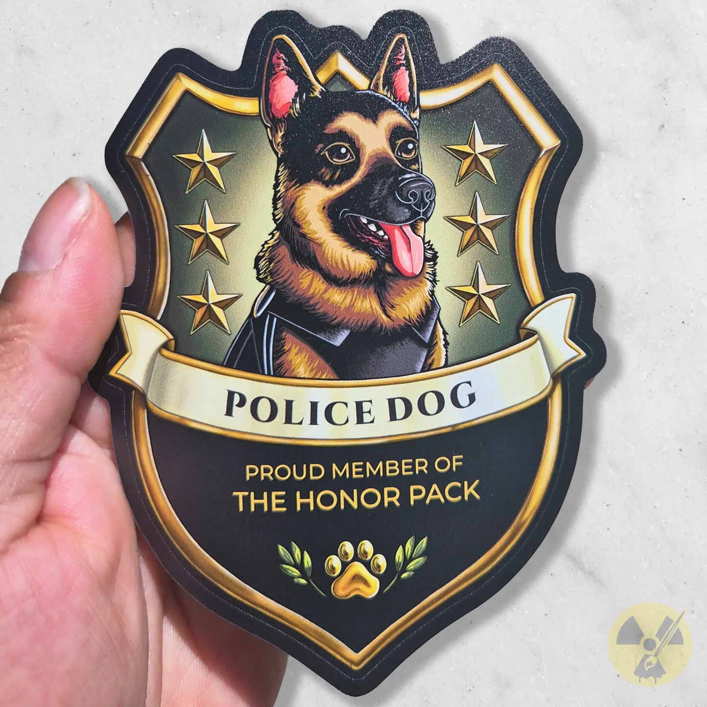 Sticker of a German Shepherd police dog Badge with stars and text held in a hand against a blurred background