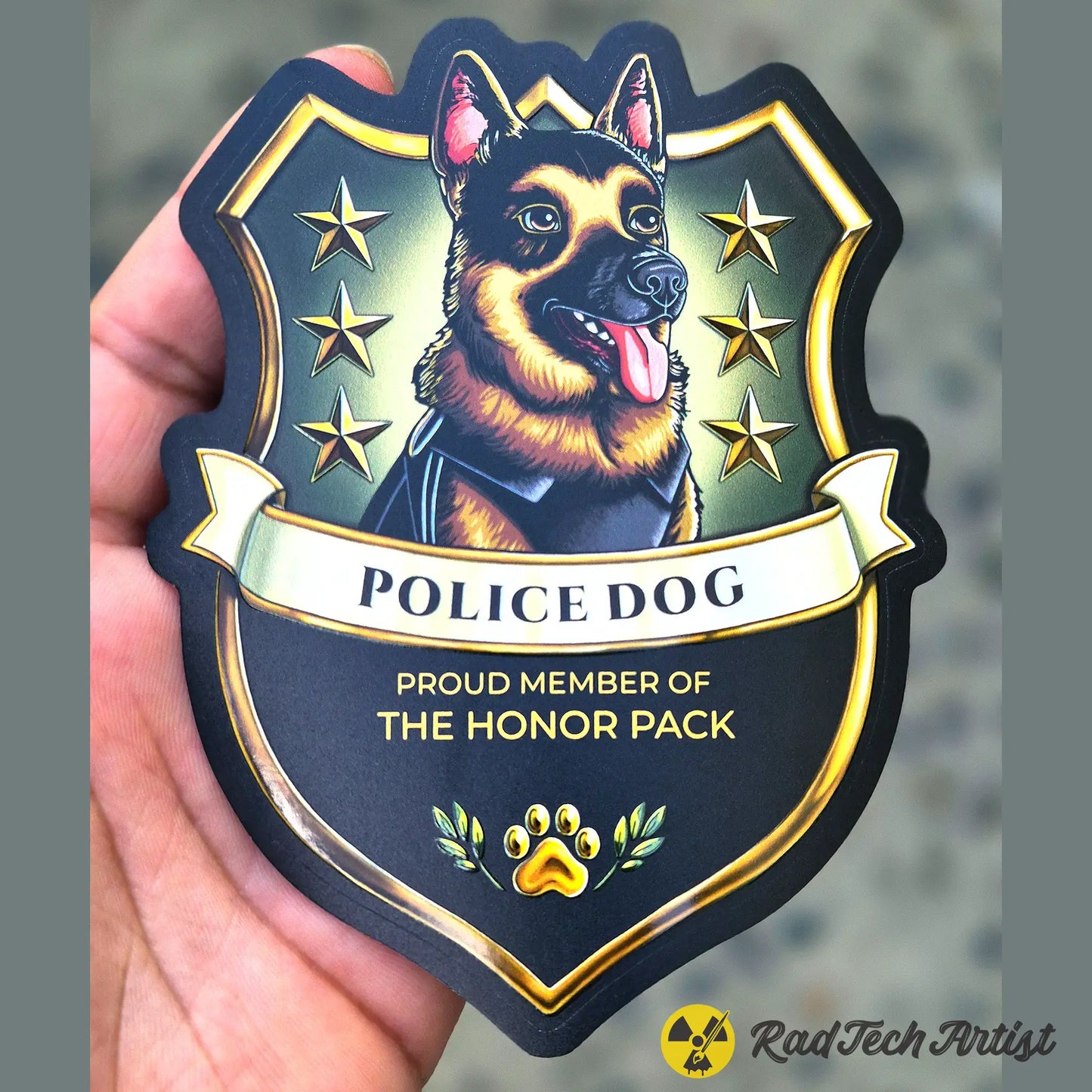 Sticker of a German Shepherd police dog Badge with stars and text held in a hand against a blurred background