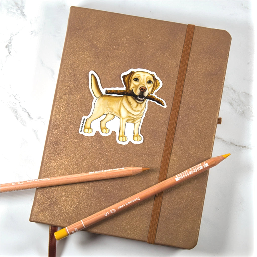 Brown notebook with a yellow Labrador Retriever Sticker and two pencils on a marble surface