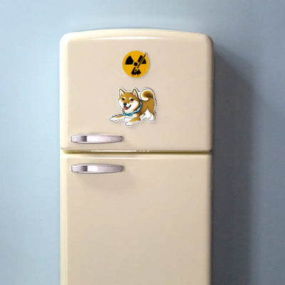 Shiba Inu dog magnet with red coat and blue bandana displayed on a beige mini fridge with light blue background.