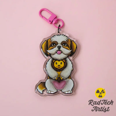 Acrylic Shih Tzu keychain with epoxy finish, showing a fluffy white and gold pup holding a plush lion toy. Attached to a pink lobster clasp, displayed on a pink background with the Rad Tech Artist logo.