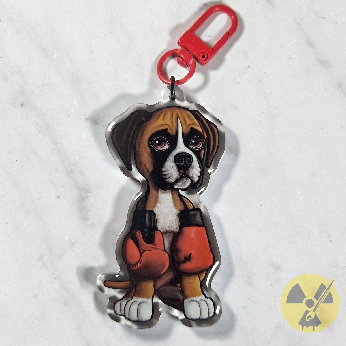 A custom acrylic keychain shaped like a Boxer puppy dog wearing red boxing gloves, featuring a red carabiner clip on a white marble background.