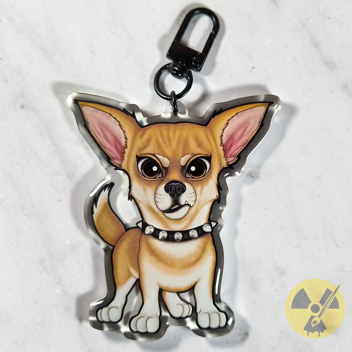 A die-cut acrylic keychain charm shaped like a cartoon Chihuahua dog wearing a spiked collar, attached to a black metal clasp, photographed on a light marble-like surface.
