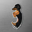 Magnet of a black and tan dachshund with a hot dog on a metallic surface