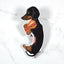 Magnet of a black and tan dachshund holding a hot dog on a marble background