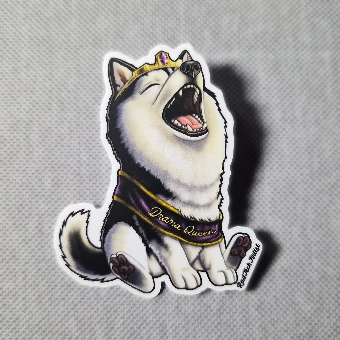 Sticker of a black and white husky dog wearing a tiara and 'Drama Queen' sash on a gray background