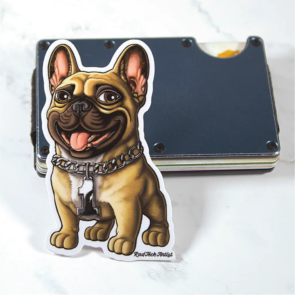 Sticker of a fawn French Bulldog with a chain leaning up against a blue wallet on a white marble background