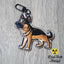 German Shepherd dog keychain featuring a black and tan standing pose, photographed on a neutral surface.