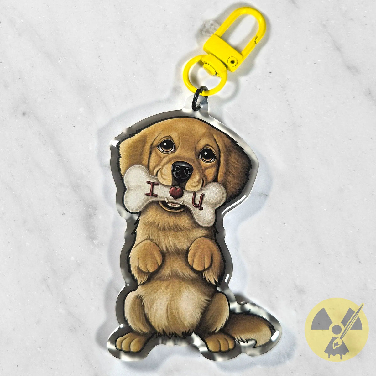 A custom acrylic keychain featuring a cartoon illustration of a golden retriever sitting and holding a bone with the text 'I love U' in its mouth. The keychain has a bright yellow swivel clasp and is photographed on a light gray marble surface.