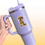 Mock-up image of a Golden Retriever vinyl sticker on a lavender tumbler cup. The sticker shows a happy golden puppy sitting upright with a large bone in its mouth. The tumbler is held by a hand with pale nail polish, set against a soft yellow background.