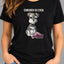 A woman wearing a black graphic t-shirt with a cartoon Schnauzer sitting on a pink slipper and the text 'CONSIDER US EVEN.' above it, paired with blue jeans.