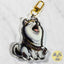 A die-cut acrylic keychain charm featuring an illustrated whining husky dog wearing a purple sash labeled 'Drama Queen' with a gold clasp, photographed on a light marble-like surface.
