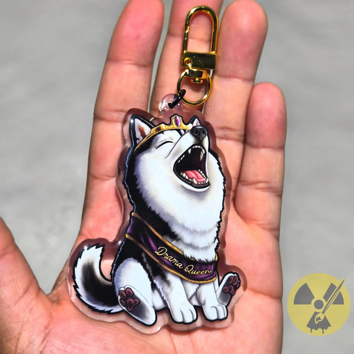 Black and White Husky Keychain, wearing a gold tiara and a purple sash reading 'Drama Queen,' held in a hand against a neutral background.