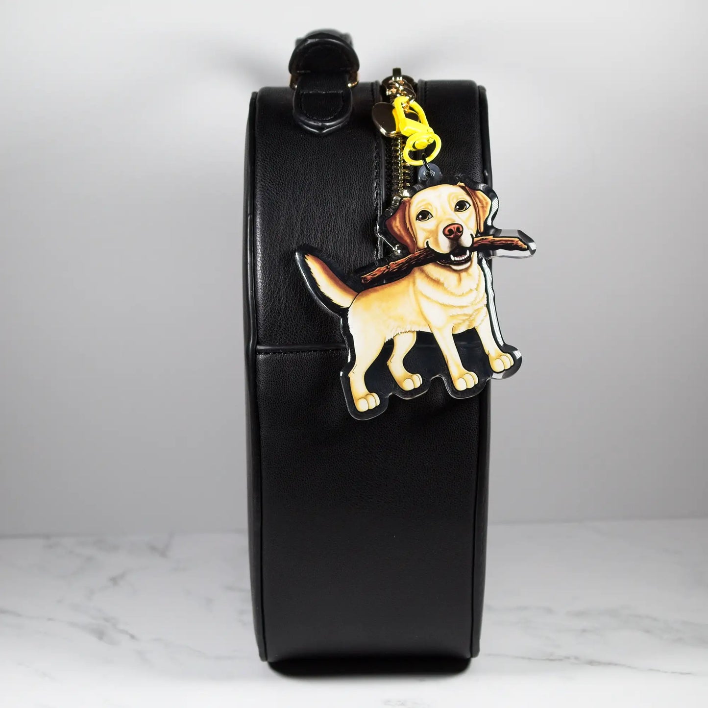 Black leather pouch with a yellow Labrador Retriever keychain on a light gray background