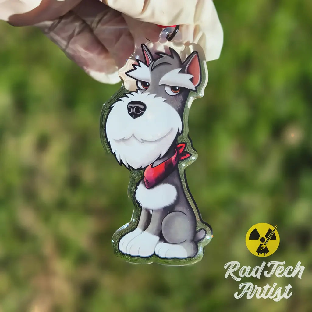 Miniature Schnauzer acrylic keychain held in hand with blurred green background, showing size and glossy epoxy finish