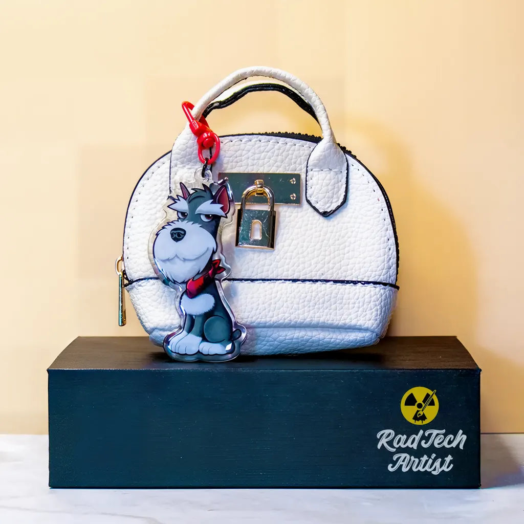 Miniature Schnauzer acrylic keychain attached to a handbag, featuring a salt and pepper schnauzer illustration with double-sided epoxy