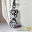Photo of a keychain of a miniature schnauzer puppy with a chewed pink slipper hanging on a white textured backpack.