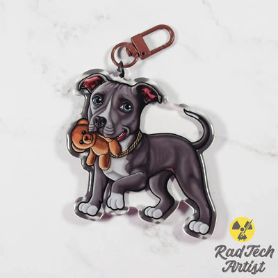 Keychain with a design of a blue and white Pit Bull holding a teddy bear on a white background