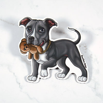 Magnet of a gray and white Pit Bull holding a teddy bear on a marble surface