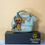 Yorkshire Terrier acrylic keychain with epoxy finish, showing a blue and gold Yorkie standing proudly. Attached to a blue lobster clasp and clipped to a mint mini purse with gold hardware, displayed on a black box with the Rad Tech Artist logo.