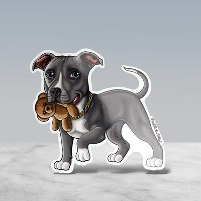 Illustrated sticker of a blue pit bull standing with a sweet expression, holding a small brown teddy bear in its mouth. The dog has white paws, a gold chain collar, and a wagging tail.