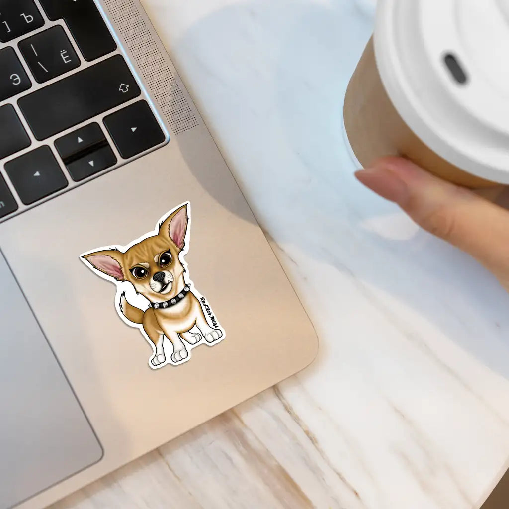 Mock-up of a fawn Chihuahua vinyl sticker with a black spiked collar on a beige laptop, next to a hand holding a coffee cup on a light marble surface.