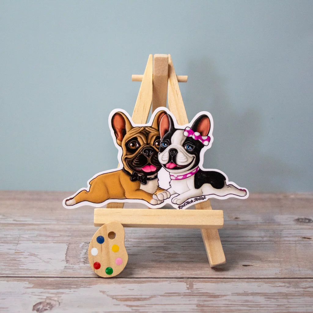Vinyl sticker of two French Bulldogs cuddling – a fawn male with a black mask and a black and white pied female with a pink bow, laying sweetly side by side with loving expressions.