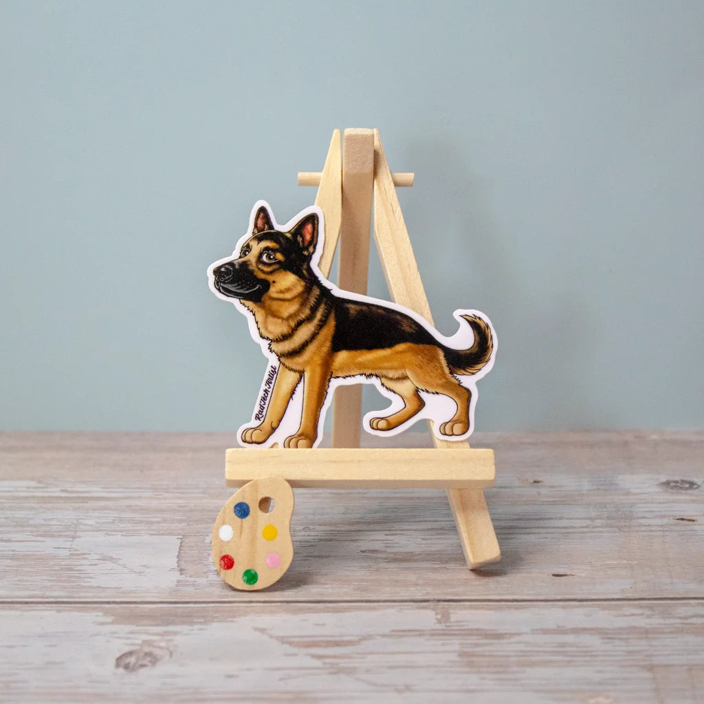 Vinyl dog sticker of a standing German Shepherd on a mini wooden easel – waterproof German Shepherd sticker for loyal dog lovers.
