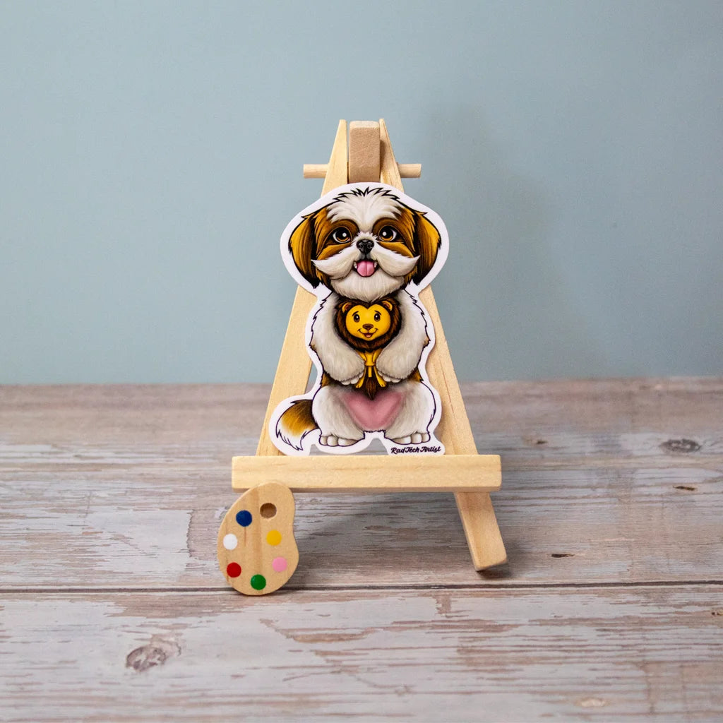 Vinyl sticker of a gold and white Shih Tzu sitting sweetly with a plush lion toy between its paws, displayed on a wooden easel with a blue background.