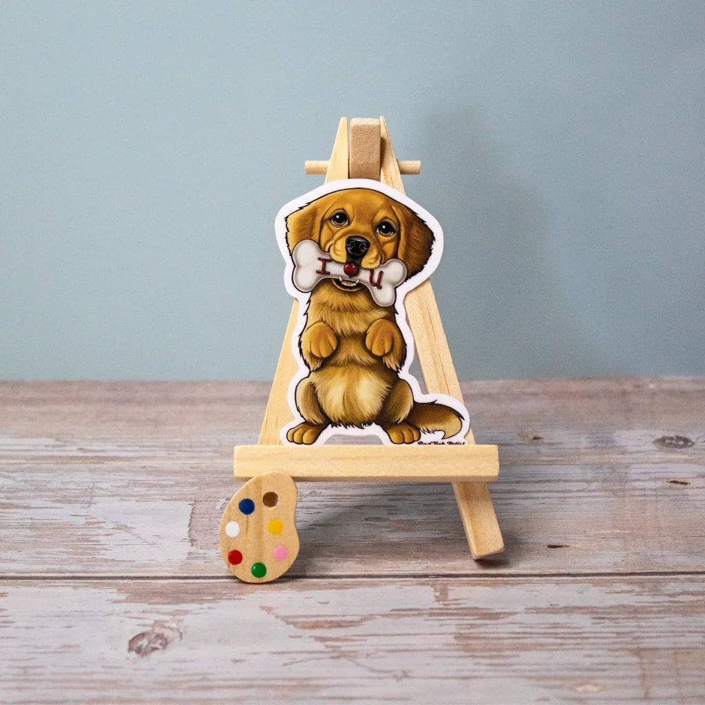 Vinyl dog sticker of a Golden Retriever puppy holding a bone on a mini wooden easel – waterproof Golden Retriever sticker for dog lovers.