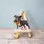 Vinyl dog sticker of a blue and white Pit Bull holding a teddy bear toy on a mini easel – waterproof Pit Bull sticker showing the breed’s gentle side.